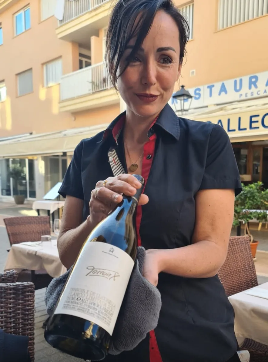 Cristina presenting a bottle of wine on the terrace